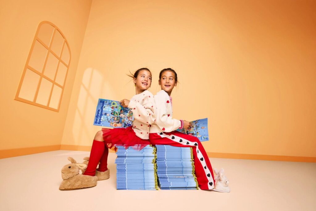 Twee kinderen zitten op een stapel speelgoedboeken van bol en bladeren erin